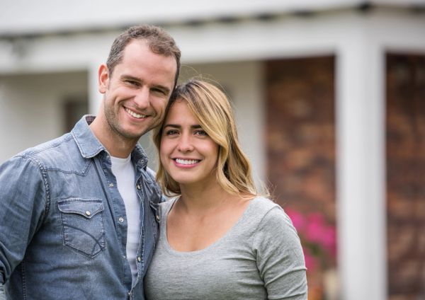 Smiling couple standing close together outdoors in casual clothes.